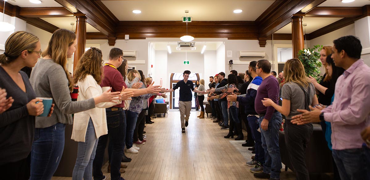 A new 360insights team member walks down a hall high-fiving his coworkers on either side.