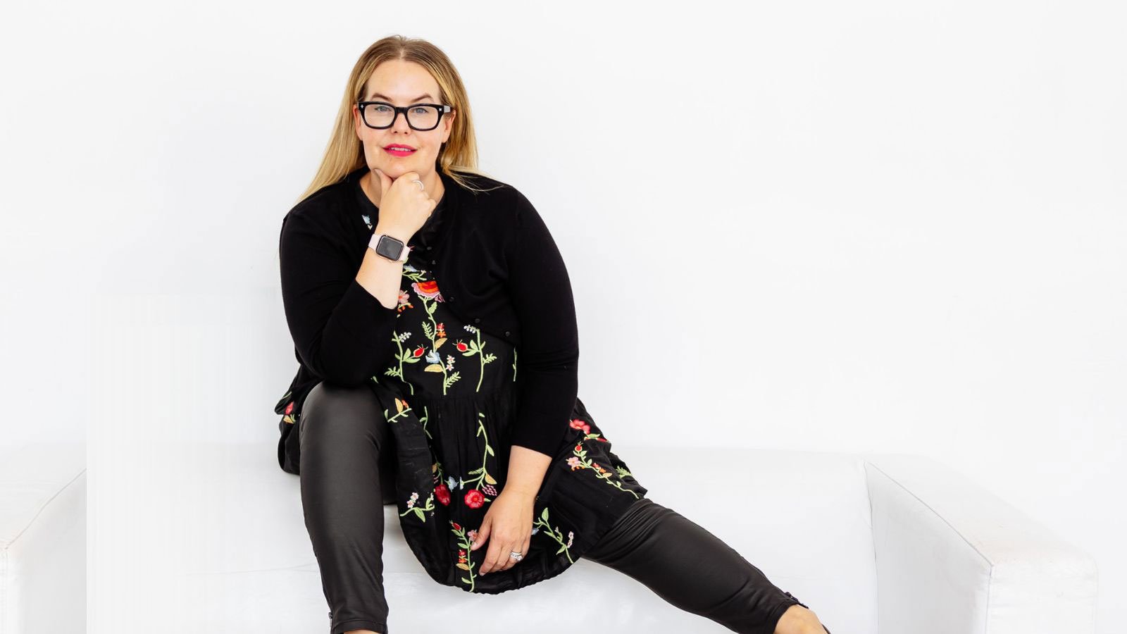 Owner Melanie Pangan sitting on back of white couch in white room