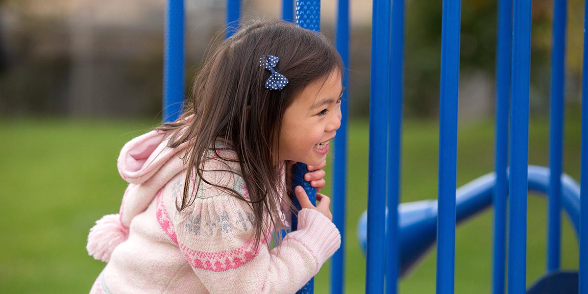 Little girl playing on park play structure.