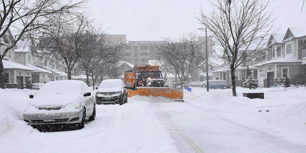 Snow plow trying to get by cars parked on road