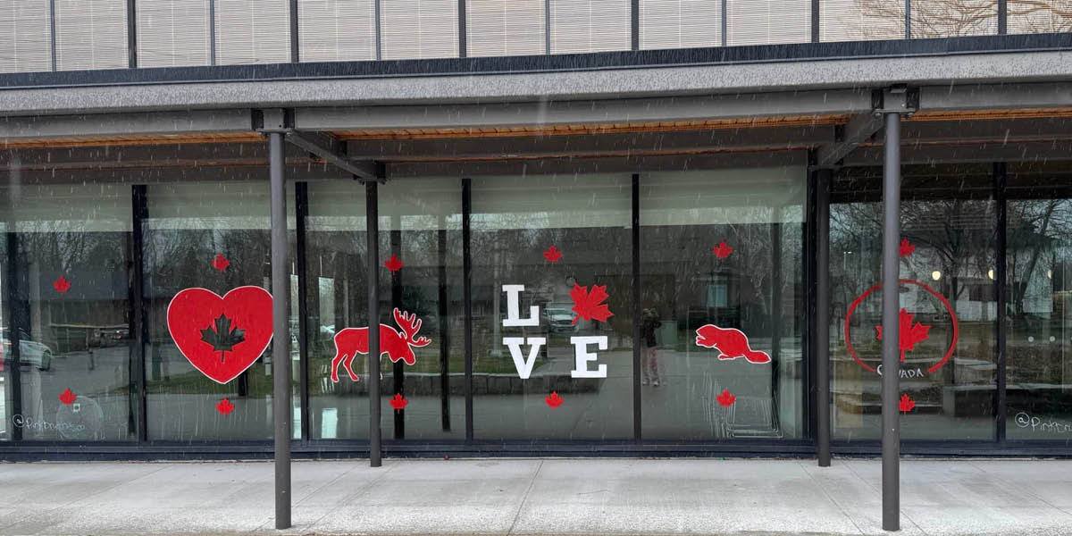 A Town facility with red a white Canadian pride paintings in the window