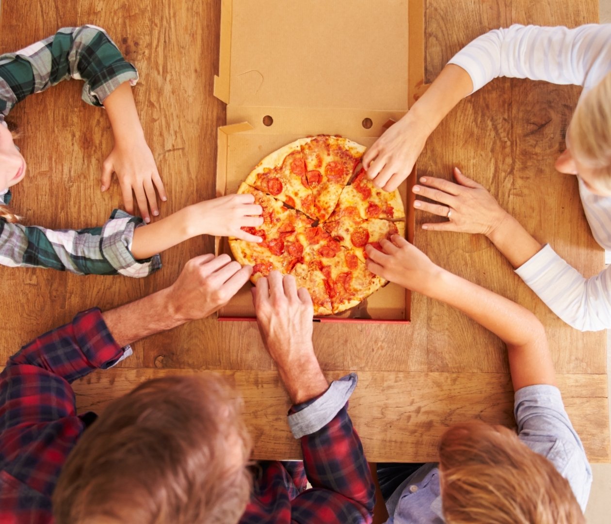 Family reaching for pizza