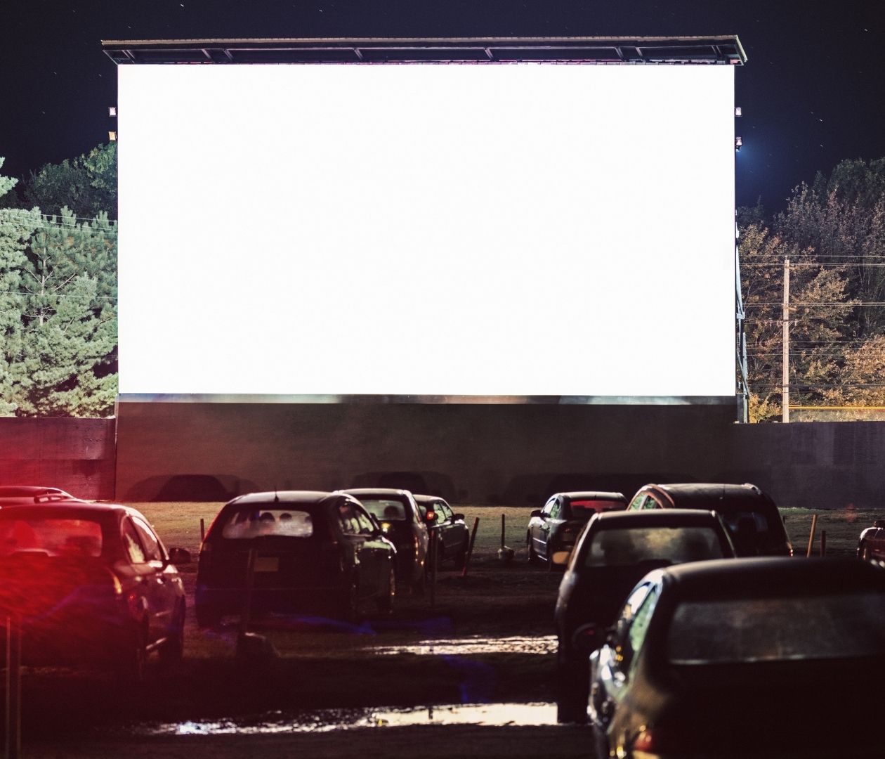 Drive in movie with cars parked in front of the screen