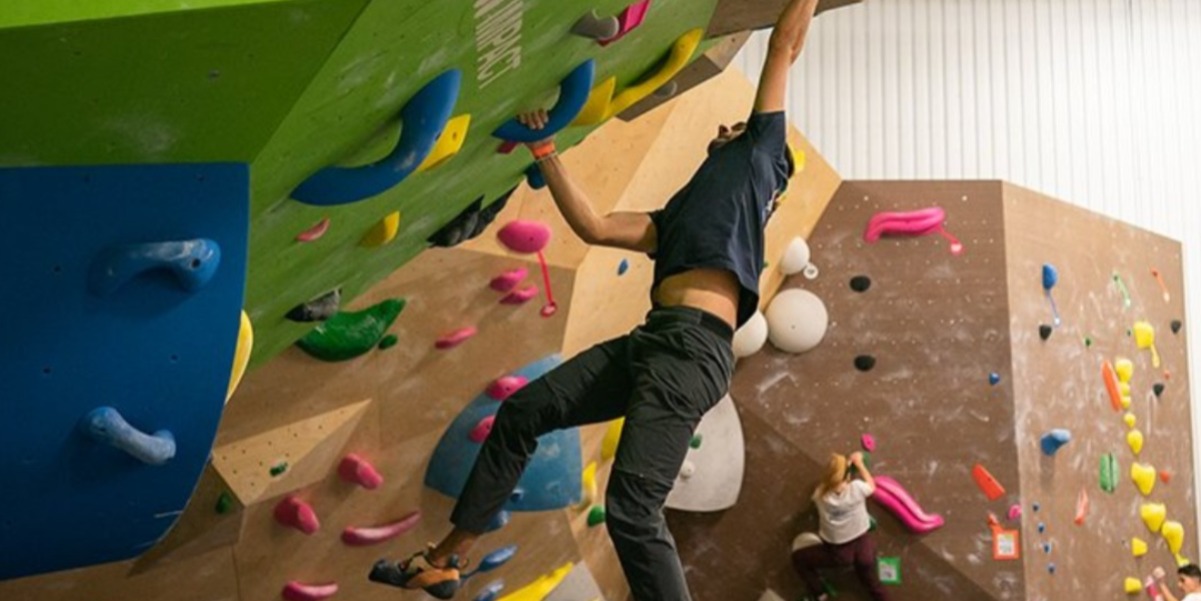 Person climbing a rock wall with people watching