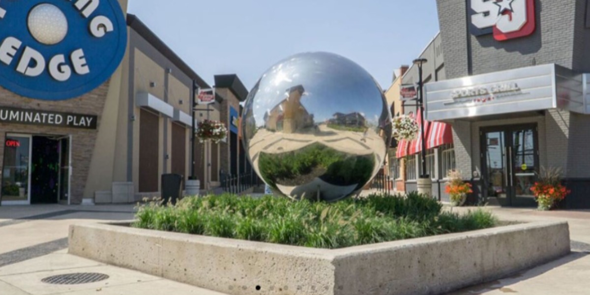 Silver ball sculpture with stores around it