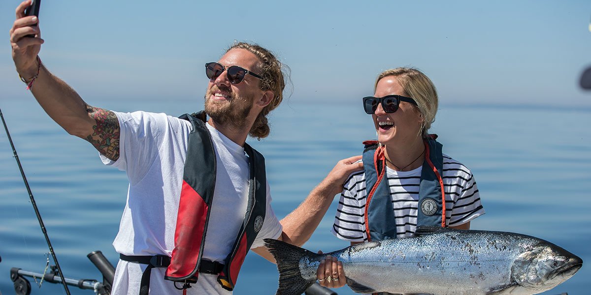 Two people taking a photo with a fish