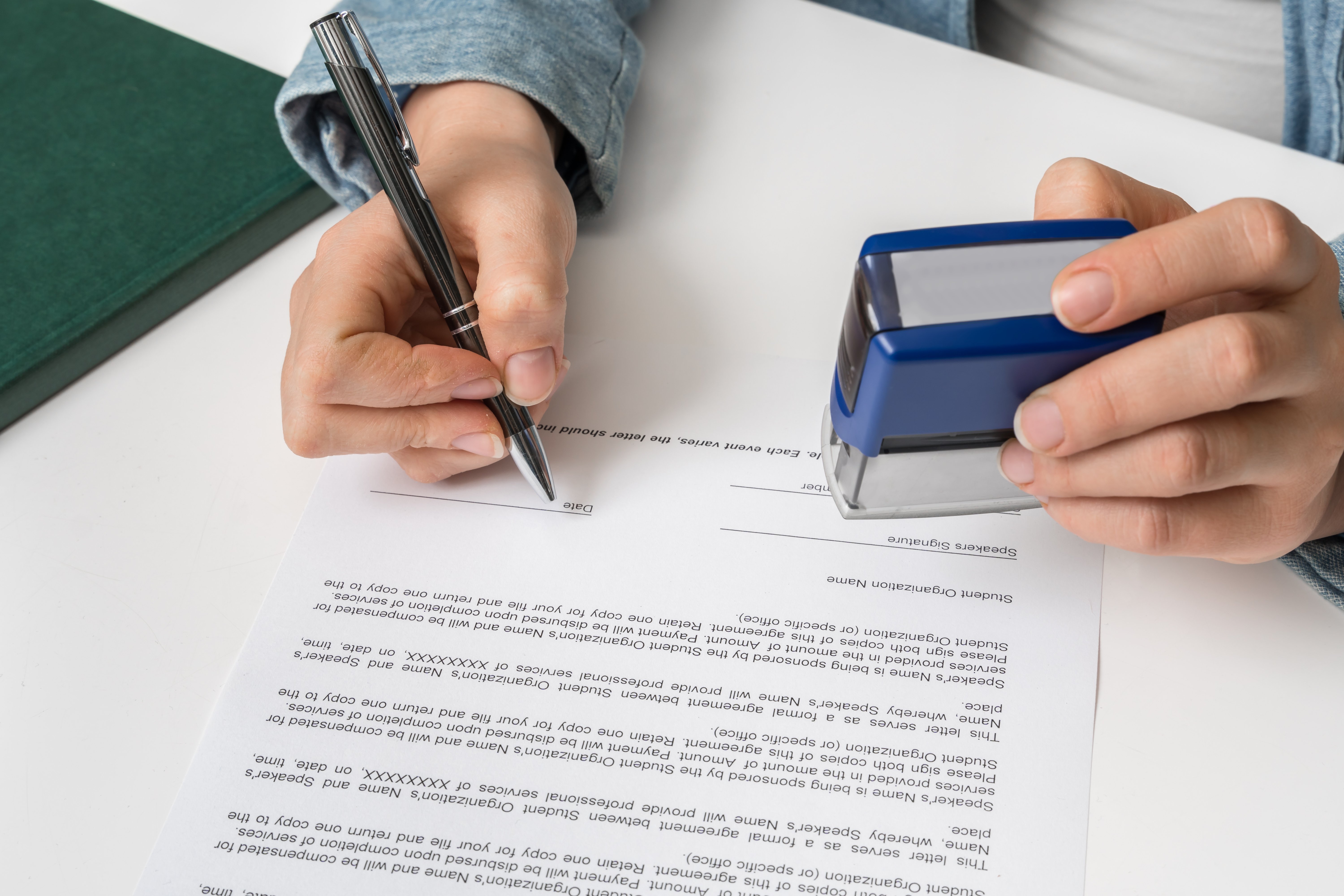 a hand holding a pen signing a document