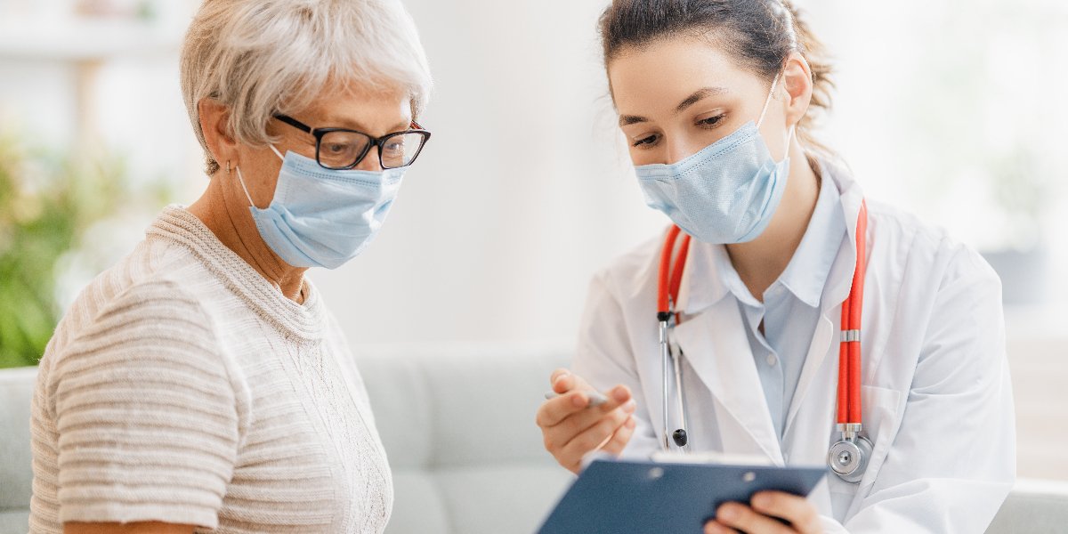 An older adult looking at a clipboard with a doctor