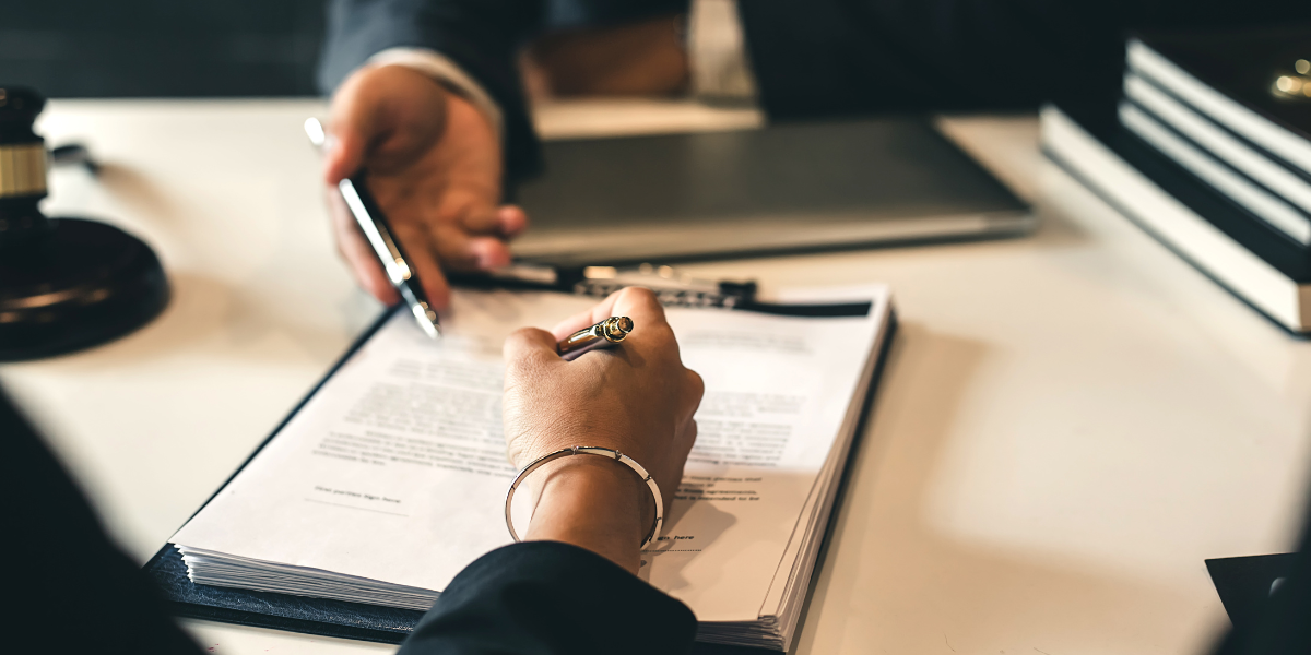 Lower half of person in suit reviewing document with person in front of them