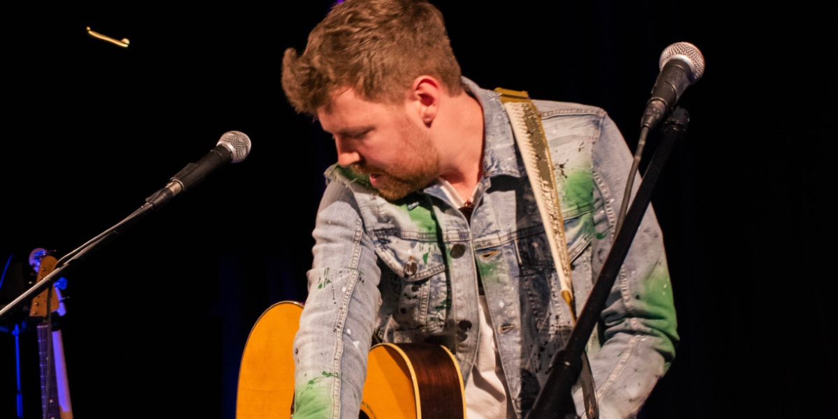 Aaron with a microphone and guitar