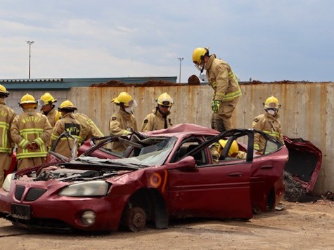 Firefighters and recruits work together to lift the roof of the vehicle.