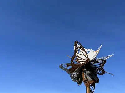 Metal butterfly sculpture against blue sky 