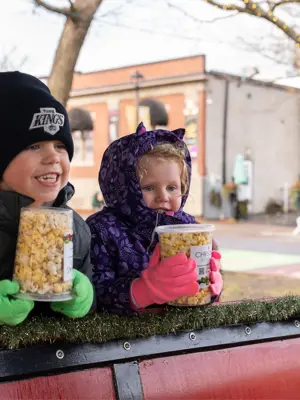 Two kids smiling on sleigh in Grass Park
