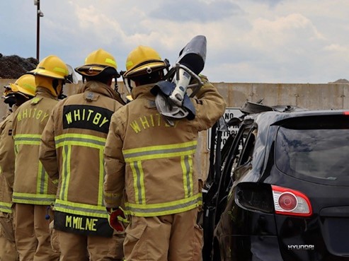 A firefighter recruit prepares to use the jaws of life to remove the vehicle door.