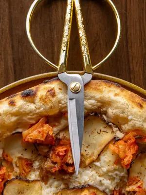 Vegan pizza with fancy scissors laying on crust 