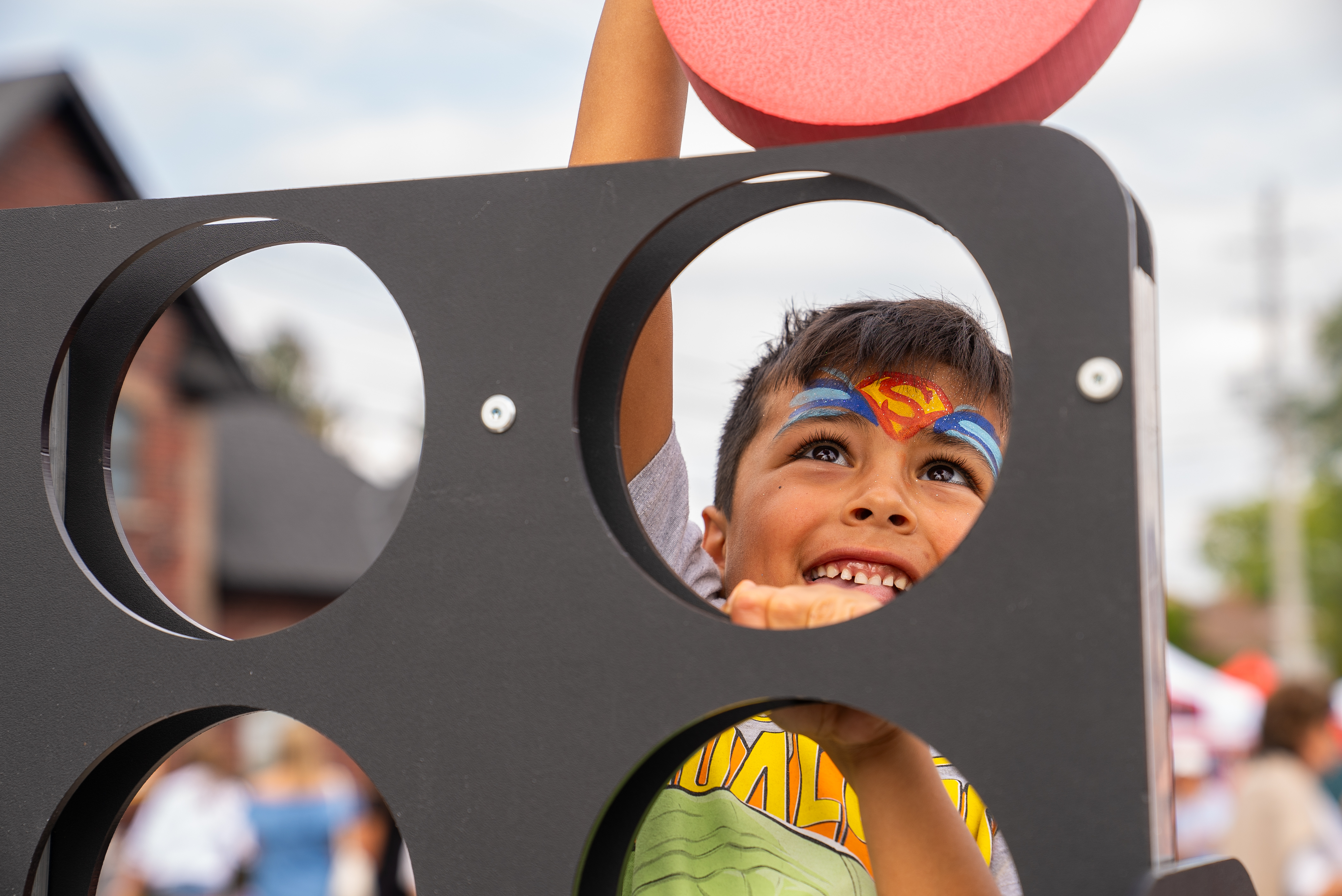 Child playing large connect four with superman face paint 