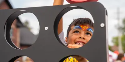 Child playing large connect four with superman face paint