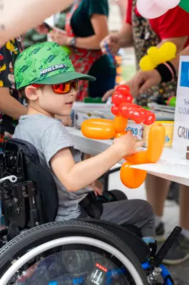 Child in wheel chair holding balloon animal 