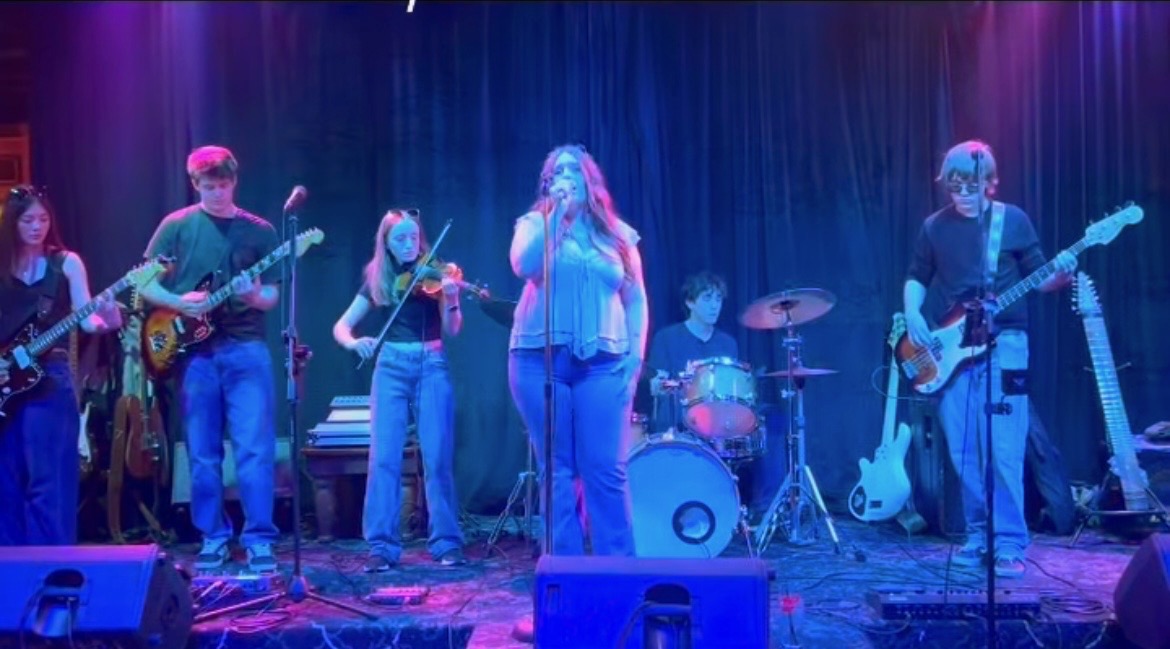 People standing on a stage with microphone and instruments