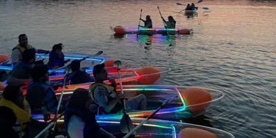 Group of people on light up kayaks at night 